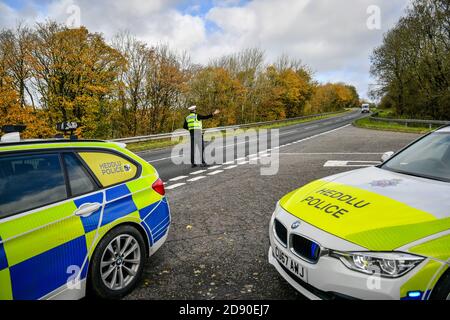 Walisische Polizei zieht Autos an einem Kontrollpunkt während Feuerbremsfahrzeuge Patrouillen nahe der Grenze zwischen Camarthenshire und Pembrokeshire, Wales. Erster Minister Mark Drakeford wird am Montag neue nationale Coronavirus-Maßnahmen für Wales vorstellen. Stockfoto