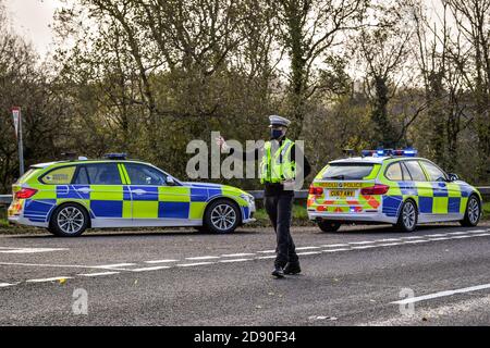 Walisische Polizei zieht Autos an einem Kontrollpunkt während Feuerbremsfahrzeuge Patrouillen nahe der Grenze zwischen Camarthenshire und Pembrokeshire, Wales. Erster Minister Mark Drakeford wird am Montag neue nationale Coronavirus-Maßnahmen für Wales vorstellen. Stockfoto