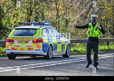 Walisische Polizei zieht Autos an einem Kontrollpunkt während Feuerbremsfahrzeuge Patrouillen nahe der Grenze zwischen Camarthenshire und Pembrokeshire, Wales. Erster Minister Mark Drakeford wird am Montag neue nationale Coronavirus-Maßnahmen für Wales vorstellen. Stockfoto