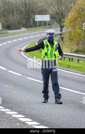 Walisische Polizei zieht Autos an einem Kontrollpunkt während Feuerbremsfahrzeuge Patrouillen nahe der Grenze zwischen Camarthenshire und Pembrokeshire, Wales. Erster Minister Mark Drakeford wird am Montag neue nationale Coronavirus-Maßnahmen für Wales vorstellen. Stockfoto