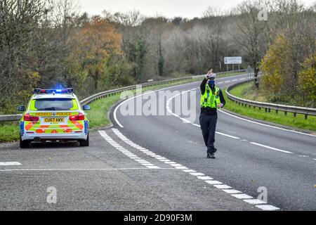 Walisische Polizei zieht Autos an einem Kontrollpunkt während Feuerbremsfahrzeuge Patrouillen nahe der Grenze zwischen Camarthenshire und Pembrokeshire, Wales. Erster Minister Mark Drakeford wird am Montag neue nationale Coronavirus-Maßnahmen für Wales vorstellen. Stockfoto