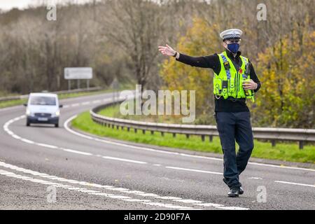 Walisische Polizei zieht Autos an einem Kontrollpunkt während Feuerbremsfahrzeuge Patrouillen nahe der Grenze zwischen Camarthenshire und Pembrokeshire, Wales. Erster Minister Mark Drakeford wird am Montag neue nationale Coronavirus-Maßnahmen für Wales vorstellen. Stockfoto