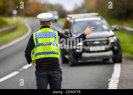 Walisische Polizei zieht Autos an einem Kontrollpunkt während Feuerbremsfahrzeuge Patrouillen nahe der Grenze zwischen Camarthenshire und Pembrokeshire, Wales. Erster Minister Mark Drakeford wird am Montag neue nationale Coronavirus-Maßnahmen für Wales vorstellen. Stockfoto