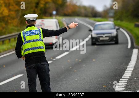 Walisische Polizei zieht Autos an einem Kontrollpunkt während Feuerbremsfahrzeuge Patrouillen nahe der Grenze zwischen Camarthenshire und Pembrokeshire, Wales. Erster Minister Mark Drakeford wird am Montag neue nationale Coronavirus-Maßnahmen für Wales vorstellen. Stockfoto