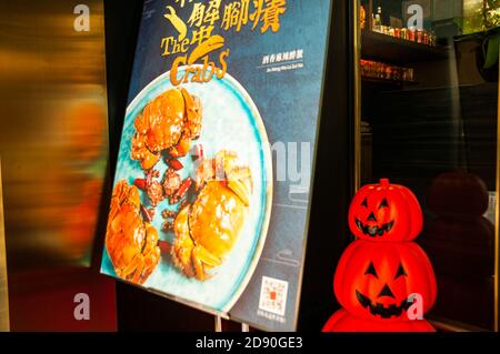 Ein Schild, auf dem haarige Krabben in einem Restaurant in Shanghais Fumin Road mit gruseligen Kürbisdekorationen für Halloween angezeigt werden. Stockfoto