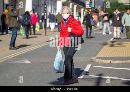 Ältere Dame in roter Jacke mit Shopping in Leamington Spa, Warwickshire, als ein weiterer Monat lang Lockdown Webs für Großbritannien Stockfoto