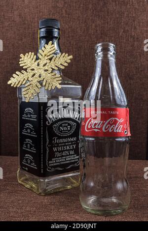 Weihnachtsfeiertagskonzept, Jack Daniel buttle weihnachtsbaum und Coca Cola, perfekte Kombination Geschenk, Gold flattern Schneeflocken Dekoration Stockfoto