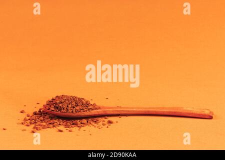 Holzlöffel mit Instant granuliertem Kaffee auf einem orange gelb Hintergrund mit einem Kopierbereich Stockfoto