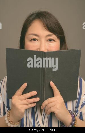 Reifen schöne asiatische Geschäftsfrau gegen grauer Hintergrund Stockfoto