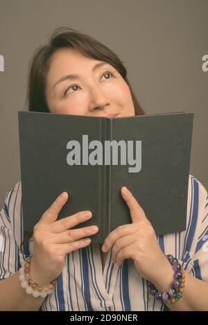 Reifen schöne asiatische Geschäftsfrau gegen grauer Hintergrund Stockfoto