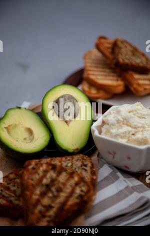 Sandwiches mit Weichkäse, Avocado und Gurke. Frühstück ist auf dem Tisch. Gesunde Ernährung. Toasten und darauf verteilen. Avocado Sandwich Stillleben Stockfoto