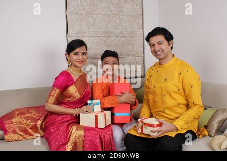 Smart indische Familie von drei in ethnischen tragen halten Diwali Geschenke. Stockfoto