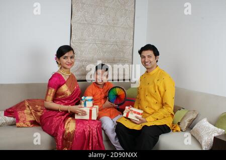 Smart indische Familie von drei in ethnischen tragen halten Diwali Geschenke. Stockfoto