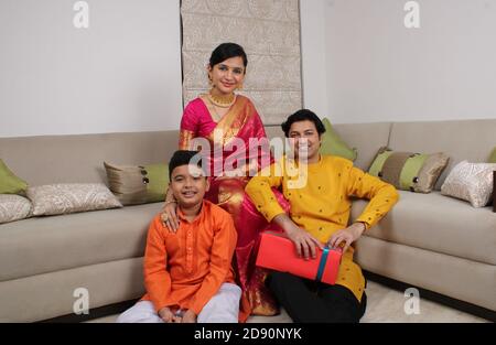 Smart indische Familie von drei in ethnischen tragen halten Diwali Geschenke. Stockfoto