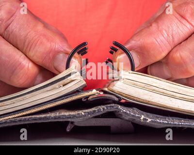 Nahaufnahme POV Aufnahme der Hände eines Mannes Öffnen oder Schließen der Ringe eines schwarzen Leder persönlichen Organizer / Organizer. Stockfoto