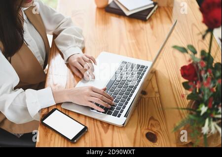 Kurze Aufnahme der jungen Frau, die an ihrem Projekt mit einem Laptop-Computer im modernen Büro arbeitet. Stockfoto