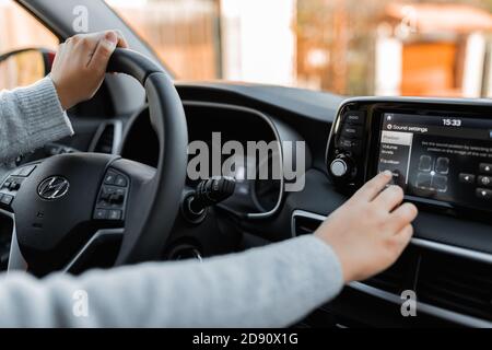 Innenansicht des nagelneuen Autos. Der Fahrer passt die Sprache des Fahrzeugs über das Bedienfeld an. Stockfoto