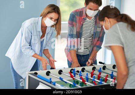Ein paar Studenten tragen Masken spielen Tischfußball in der campus Stockfoto