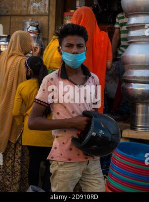 Jaisalmer, Rajasthan / Indien - november 02 2020 : Kid nicht tragen Maske richtig und hält Helm auf der Hand auf dem Markt Stockfoto