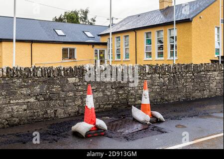 Timoleague, West Cork, Irland. November 2020. Die Straße vor der Timoleague National School wurde über Nacht durch unaufhörlichen, starken Regen nach einem Wetterwarnsystem von Eireann beschädigt. Der rat legte Verkehrskegel an, um die Verkehrsteilnehmer vor dem Schaden zu warnen. Quelle: AG News/Alamy Live News Stockfoto