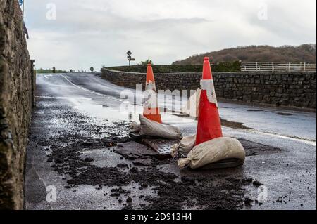 Timoleague, West Cork, Irland. November 2020. Die Straße vor der Timoleague National School wurde über Nacht durch unaufhörlichen, starken Regen nach einem Wetterwarnsystem von Eireann beschädigt. Der rat legte Verkehrskegel an, um die Verkehrsteilnehmer vor dem Schaden zu warnen. Quelle: AG News/Alamy Live News Stockfoto