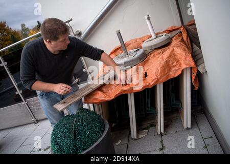 02. November 2020, Niedersachsen, Achim: Claus Meyer, Leiter des Restaurants "zur Linde" (Meyer Bierden), räumt auf seinem Balkon die Tische ab. Am Montag, 02.11.2020, hat in ganz Deutschland eine teilweise Sperrung begonnen, um die Ausbreitung des Coronavirus zu verlangsamen. Restaurants sind geschlossen, Lieferservice und Essen zum Mitnehmen sind weiterhin erlaubt. Foto: Sina Schuldt/dpa Stockfoto