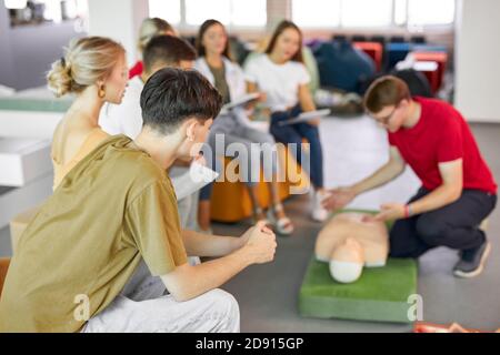 Gruppe von jungen kaukasischen Menschen lernen, wie man ein Leben sicher sitzen zusammen in der Lektion, diskutieren alle Techniken, mit Schaufensterpuppe ein Beispiel zu zeigen Stockfoto