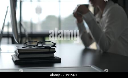 Eine Brille, die auf dem Bücherstapel im Büro platziert wird. Stockfoto