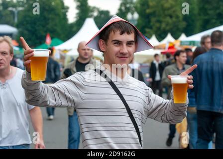 Junger Mann mit zwei Plastikbiergläsern bei einem Straßenbierfest. Moskau, Russland, 09.07.2009 Stockfoto