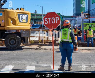 Eine Bauarbeiterin hält ein Schild, um den Verkehr auf einer Baustelle auf der Second Avenue im Sunset Park, Brooklyn, zu kontrollieren Stockfoto