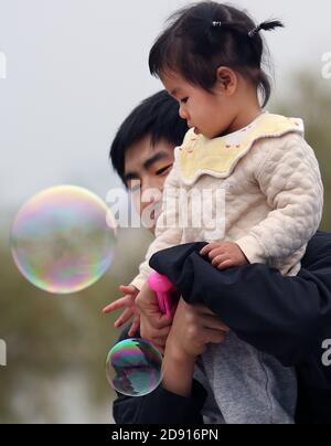 Wuhan, China. November 2020. Ein Vater hält seine Tochter, die von Blasen fasziniert ist, am Sonntag, den 1. November 2020 in einem Park in Wuhan, der Hauptstadt der Provinz Hubei. Chinas Geburtenrate verlangsamte sich im vergangenen Jahr auf den niedrigsten Stand seit der Gründung der Volksrepublik China im Jahr 1949, was die Sorge um eine langfristige Herausforderung für die Regierung noch zusätzlich erhöht, da die grauende Gesellschaft und die schrumpfende Belegschaft Druck auf eine verlangsamte Wirtschaft anhäufen. Foto von Stephen Shaver/UPI Kredit: UPI/Alamy Live Nachrichten Stockfoto