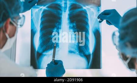 Nahaufnahme. Ärzte in Schutzkleidung diskutieren eine Röntgenaufnahme der Lunge . Stockfoto