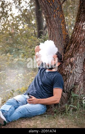 Schöner Vaper genießen eine elektronische Zigarette draußen. Stilvoller Mann. Stockfoto