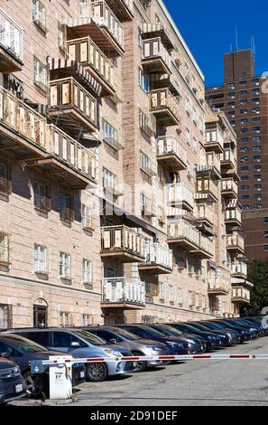 Ein Mehrfamilienhaus mit Balkonen in South Williamsburg, Brooklyn, NY. An der Seite des Gebäudes befindet sich eine lange Reihe von Autos. Stockfoto