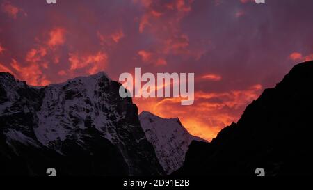 Dramatischer Sonnenuntergang mit lila und orange gefärbten Wolken im Himalaya mit schneebedeckten zerklüfteten Bergen in der Nähe von sherpa Dorf Thame, Khumbu, Nepal. Stockfoto