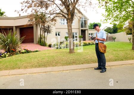 Johannesburg, Südafrika - 11. September 2010: Post Mailman Hand liefert Post in einem wohlhabenden Vorort Nachbarschaft Stockfoto