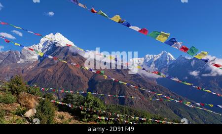 Mehrere Reihen von bunten buddhistischen Gebetsfahnen fliegen im Wind über Namche Bazar, Khumbu, Himalaya, Nepal mit majestätischem Bergpanorama. Stockfoto