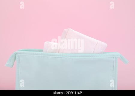Damenbinden in einer blauen Kosmetiktasche auf einem rosa Hintergrund Stockfoto