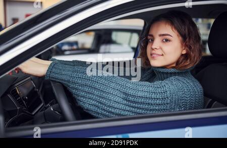 Positive junge Mädchen in legere Kleidung sitzt im Inneren der modernen Auto und Lächeln Stockfoto