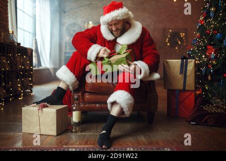 Bad Drunk Santa claus öffnet Geschenke, Humor Stockfoto