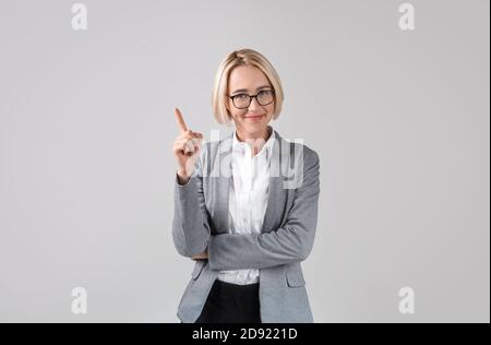 Positive Geschäftsfrau mit kreativen Idee auf hellgrauem Studio Hintergrund Stockfoto