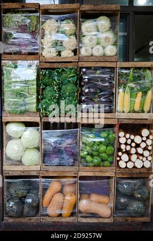 Straßenmarkt-Verkäufer mit Gemüse in Holzkisten wie Zellen verpackt, um Vielfalt von Gemüse zu demonstrieren. Kürbisse, Kohl, Mais, Salate und andere Stockfoto