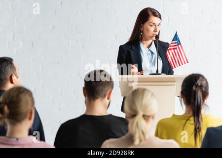 Politischer Agitator, der mit den Wählern im Konferenzsaal spricht, auf verschwommen Vordergrund Stockfoto