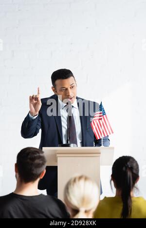 indischer politischer Agitator, der Aufmerksamkeit zeigt, während er mit Wählern im Konferenzsaal spricht, verschwommener Vordergrund Stockfoto