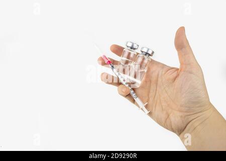 Zwei Fläschchen mit Medizin und Spritze in einer Hand für die Injektionsbehandlung. Covid-19 Impfstoffkonzept. Isoliert auf weißem Hintergrund Stockfoto