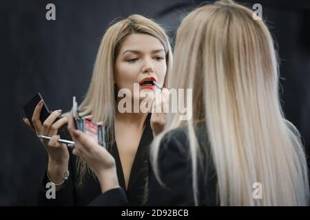 Frau, die flüssigen Lippenstift auf den Spiegel suchen Stockfoto
