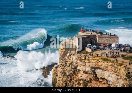 Große Wellen schlagen in der Nähe des Leuchtturms Fort von Nazare in Nazare, Portugal. Nazare ist bekannt dafür, die größten Wellen der Welt zu haben. Stockfoto