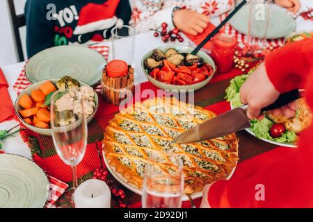 Beschnittene Ansicht der Familie, die neben einem servierten Tisch mit Kuchen sitzt Zu Hause Stockfoto