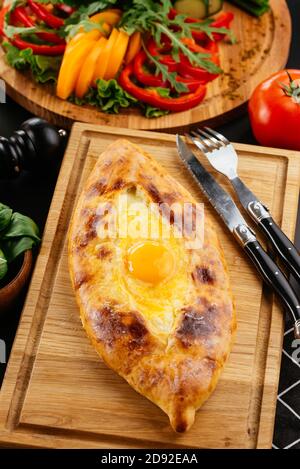 Ajarian Khachapuri traditionelle georgische Käse Gebäck mit Eiern auf Schneidebrett. Hausgemachtes Backen. Stockfoto