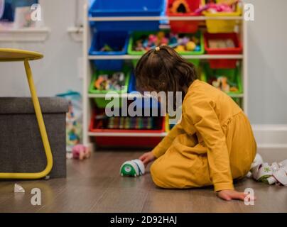 Kleines Mädchen spielt mit einem Spielzeug im Spielzimmer Stockfoto